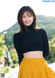 A woman in a black top and yellow skirt posing for a picture.